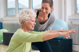 instructor helping senior woman with her exercise
